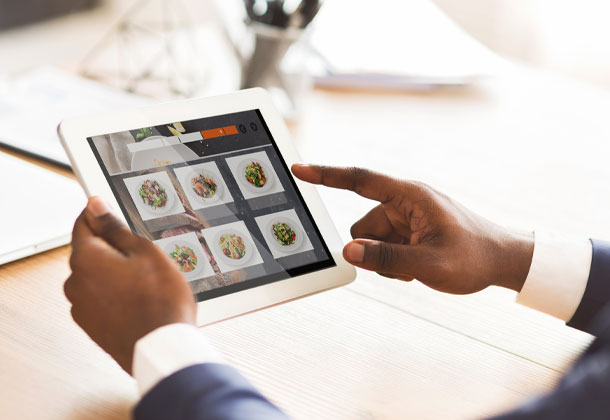 black man's hands using tablet with images of food on it