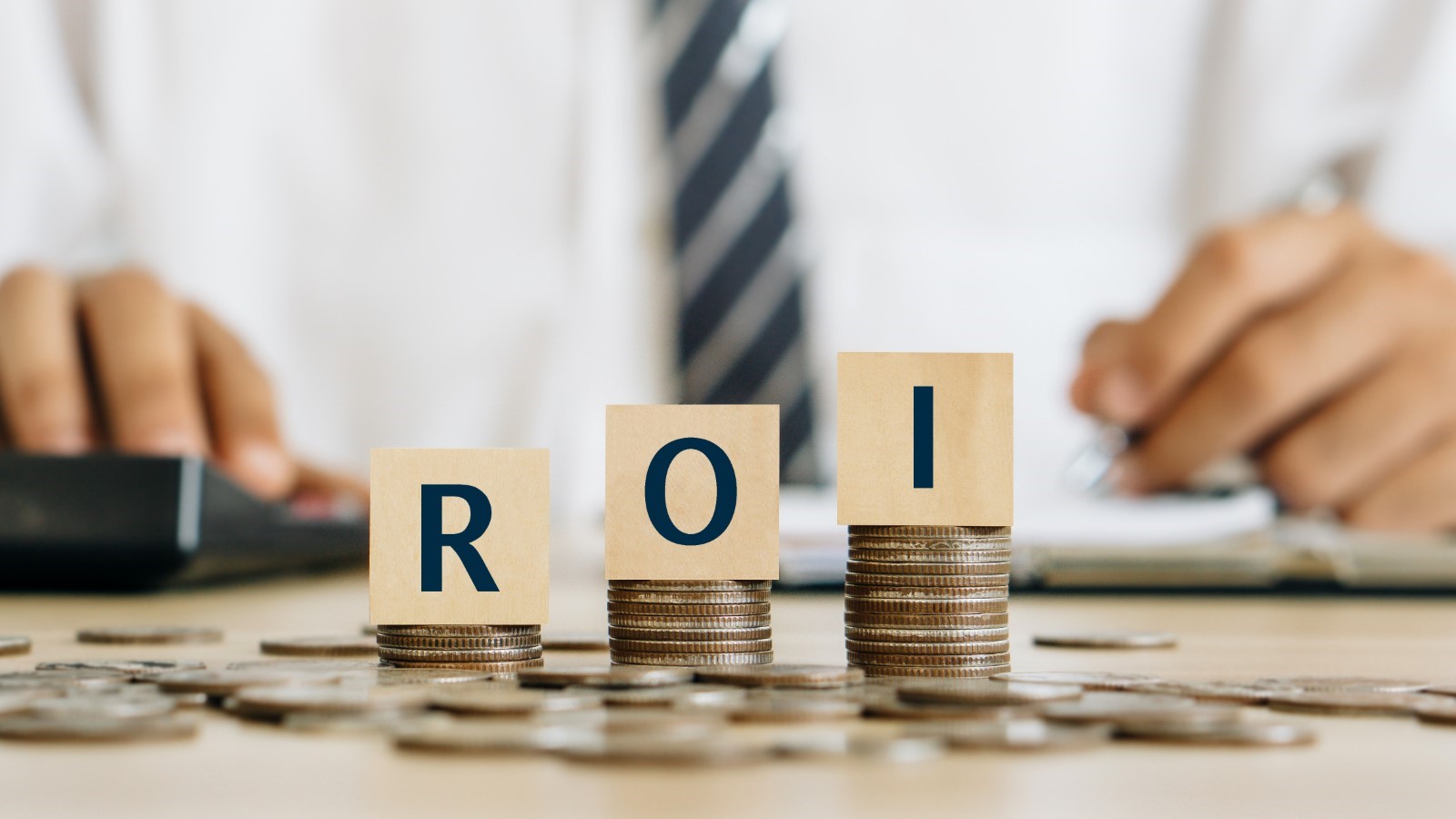 three letter blocks spelling out ROI on top of piles of coins